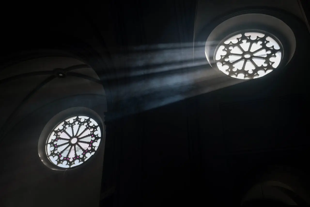 Sun rays illuminate ornate church rose windows, creating a dramatic interior scene.